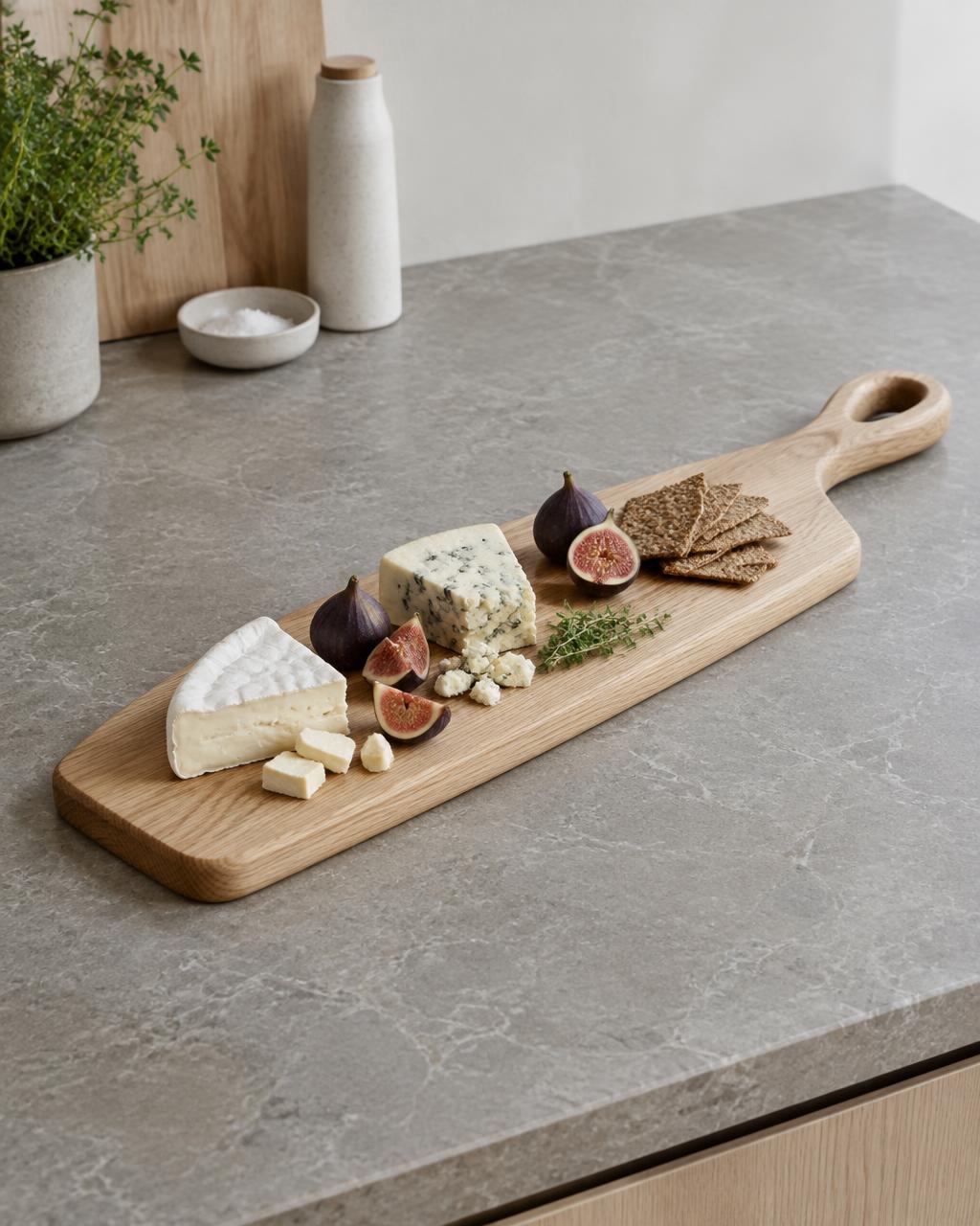 Long ash serving board with cheese and figs on a stone worktop