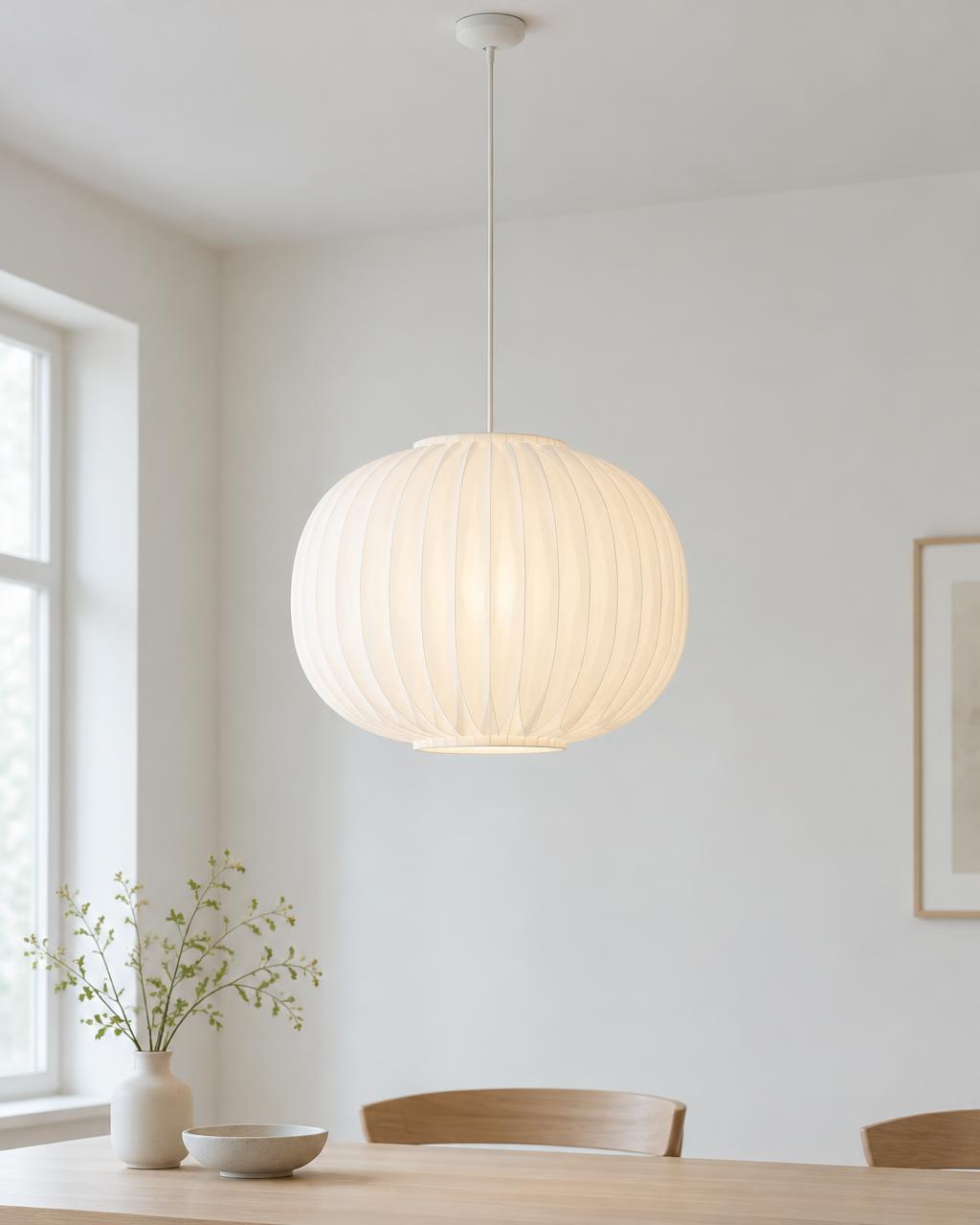 Pleated white paper pendant lamp glowing above a dining table