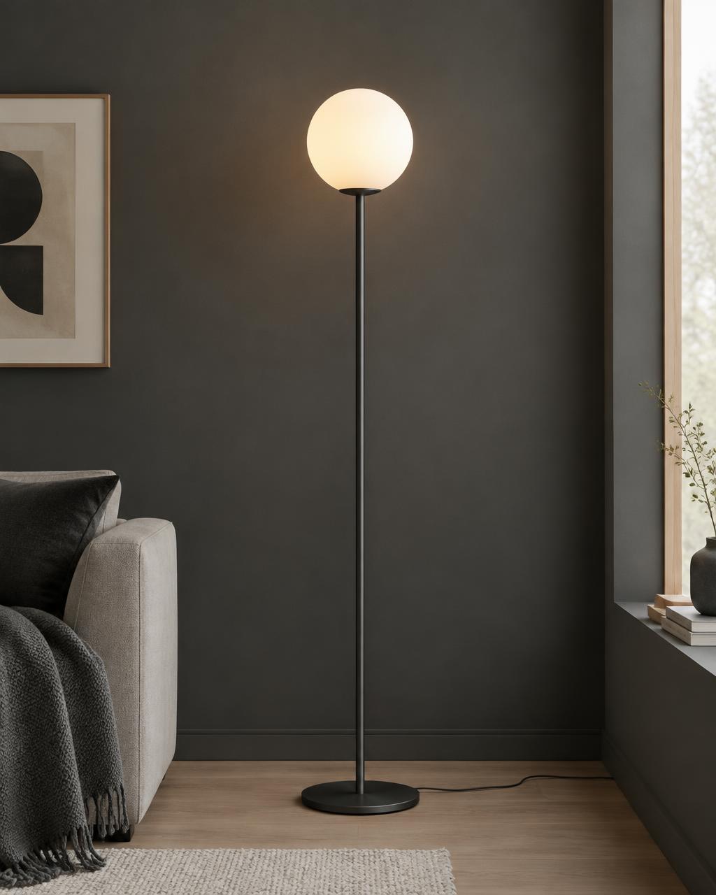 Slender black floor lamp with opal globe against a charcoal wall