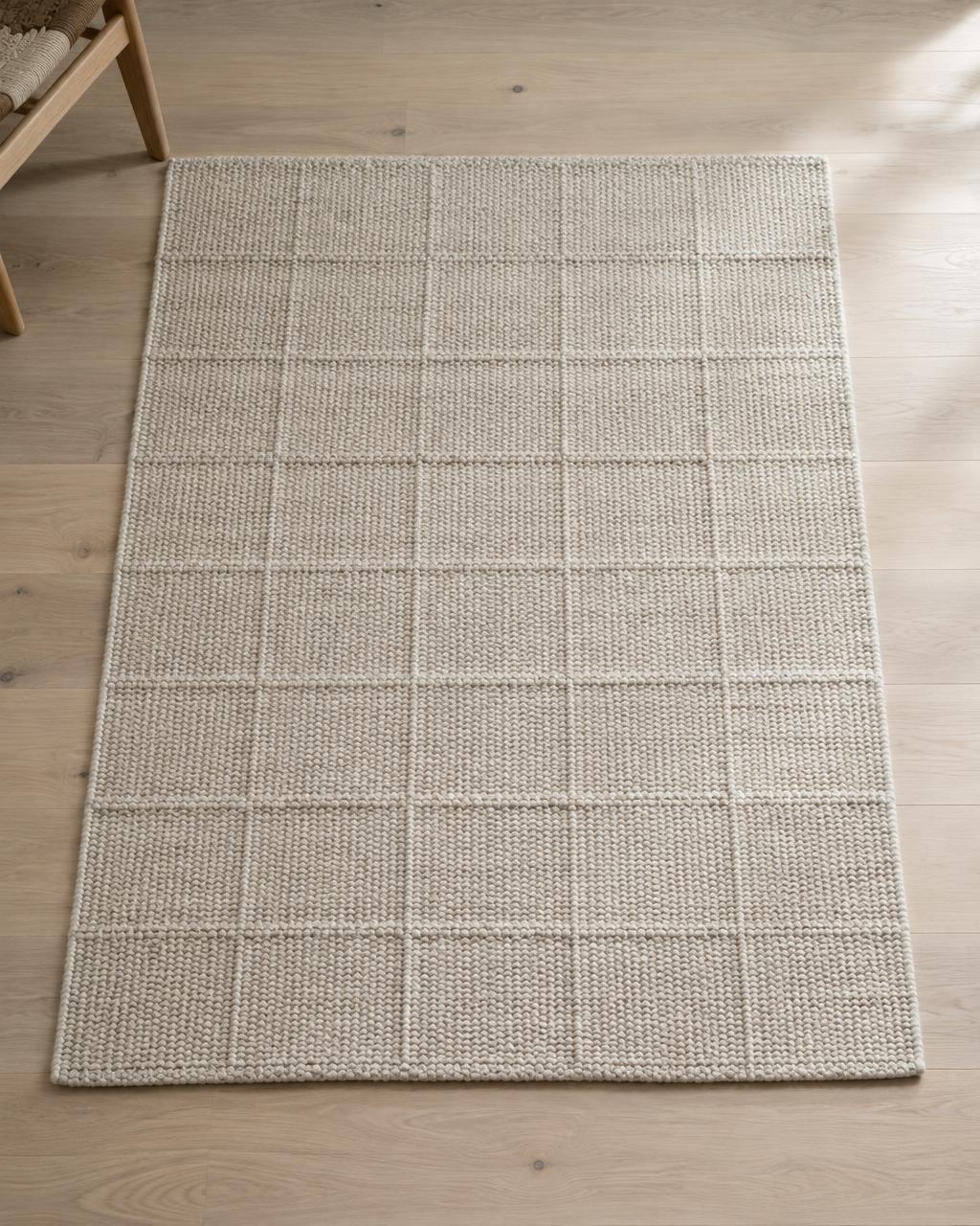 Undyed hand-woven wool rug with grid texture on a pale oak floor
