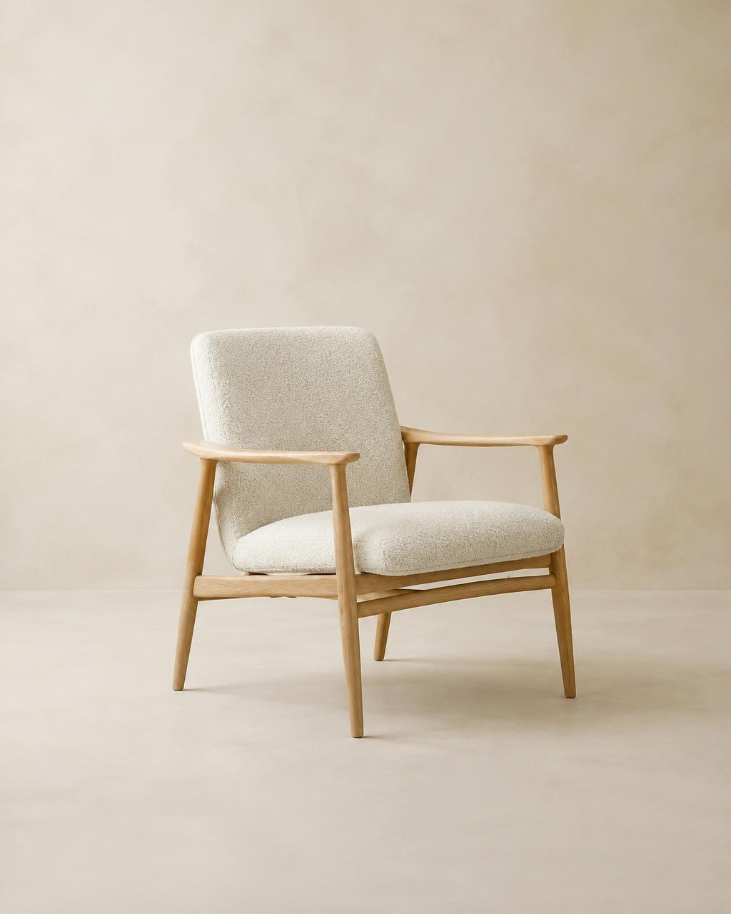 Fjord lounge chair with solid oak frame and cream bouclé seat against a warm plaster backdrop
