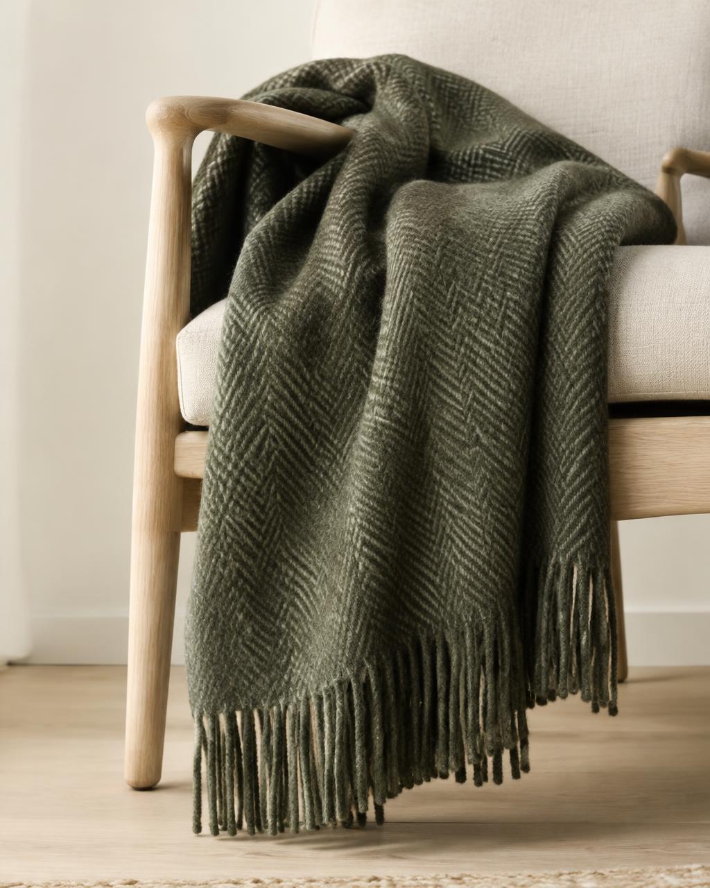 Moss-green herringbone wool throw draped over an oak armchair