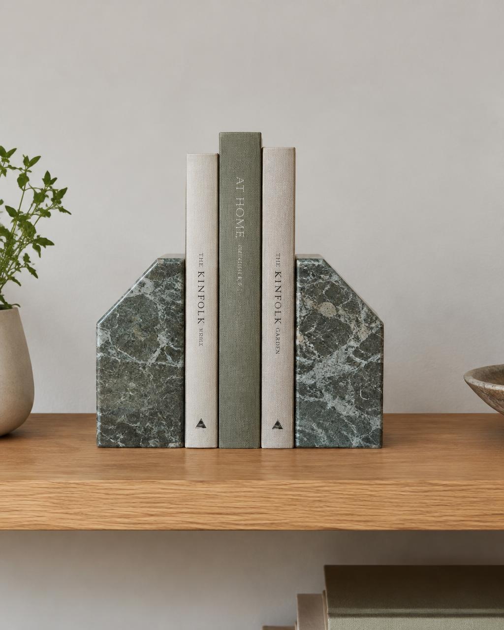 Pair of green marble bookends holding linen-bound books on an oak shelf