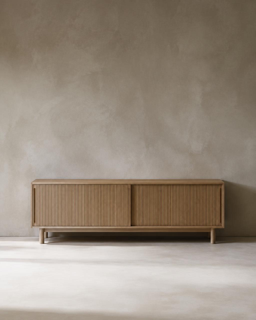 Low oak sideboard with ribbed sliding doors before a grey plaster wall